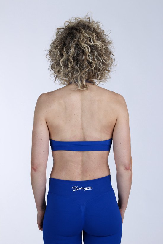 Model van achteren in een donkerblauwe sportbeha en legging. De sportbeha heeft een racerback.