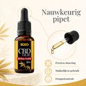 Bruine fles CBD Olie Extra Forte 30% met zwarte druppelaar, met een detailopname van de druppelaar die een druppel afgeeft.