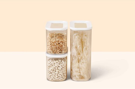 Trois boîtes de conservation Mepal Modula empilées et côte à côte. Deux avec couvercles blancs, remplies de haricots blancs et bruns.