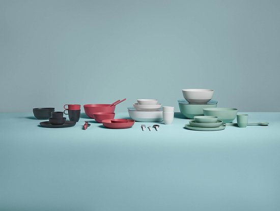 Groot assortiment serviesgoed in verschillende kleuren, waaronder roze, grijs, wit en groen. Met schalen, mokken, borden en bestek.