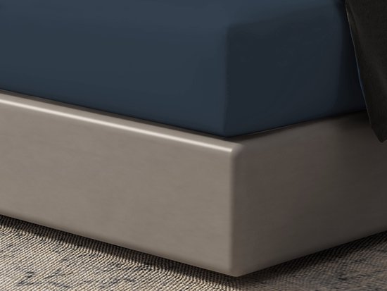 Gros plan d'un drap-housse bleu foncé sur un lit.