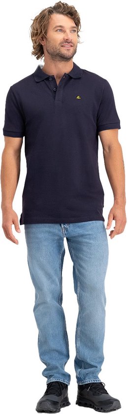 Man met kort blond haar draagt een donkerblauw NOMAD poloshirt en een spijkerbroek.