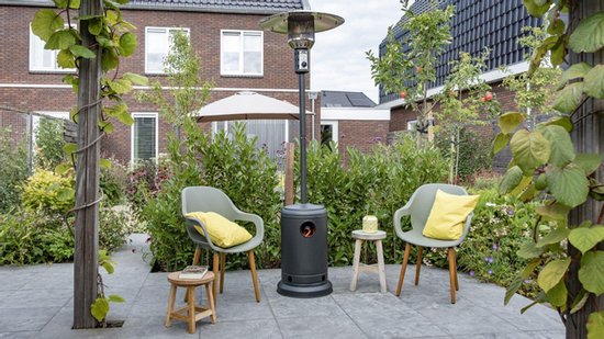 Zwarte Eurom THG terrasverwarmer op een terras met groen en huizen, naast twee stoelen en een hond.