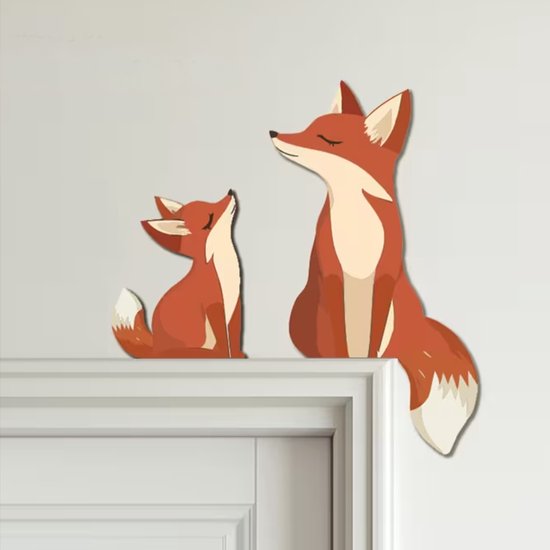Een houten decoratie van twee vossen, een grote en een kleine, zittend op een deuropening.
