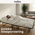 Vrouw slapend op een uitgeklapt vouwbed, 'Unieke Slaapervaring'.