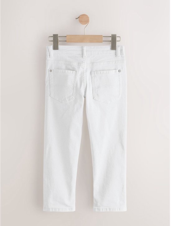 Achterkant van witte jeans met rechte pijpen, hangend aan een kledinghanger.