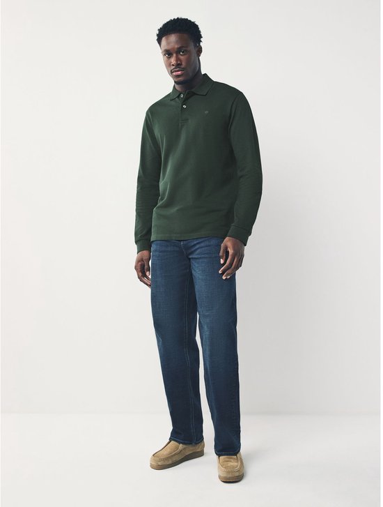 Man met donkergroen poloshirt met lange mouwen en jeans.