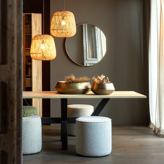 Een eettafel met twee rotan hanglampen, gouden vazen en drie poefs.