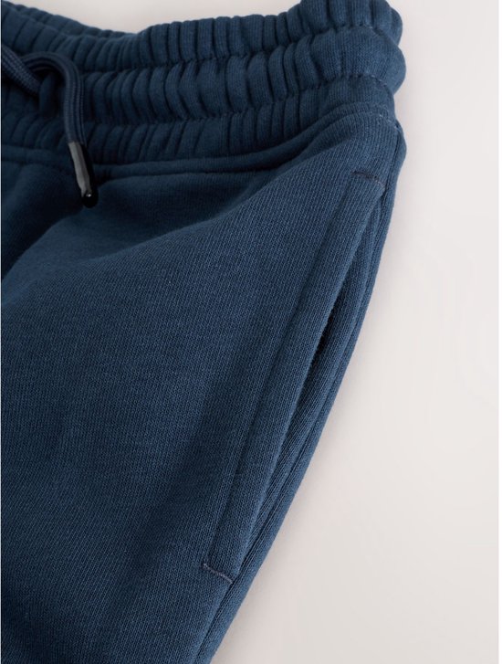 Close-up van een marineblauwe joggingbroek met zijzakken en elastische taille.