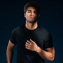Man met zwart T-shirt draagt een dunne zwarte ketting en een zwarte armband met bedeltje.