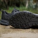 Zwarte Adidas Terrex trailrunningschoen met profielzool, op een ondergrond van zand en gras.