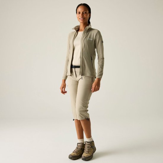 Model draagt beige fleece jas, beige shirt, beige capri broek en wandelschoenen.