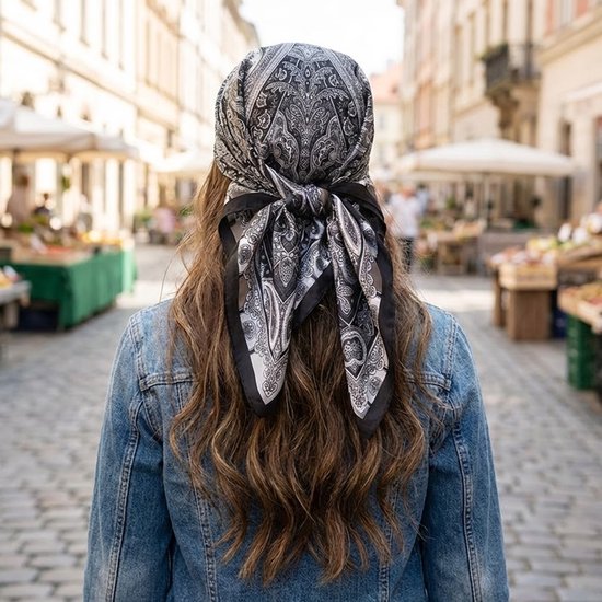 Zicht van achteren op een vrouw met lang bruin haar en een denim jack, met een zwart-witte paisley bandana gestrikt.