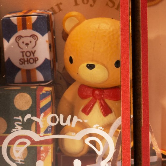 Gedetailleerde close-up van een teddybeer met rode strik in een miniatuur speelgoedwinkel.