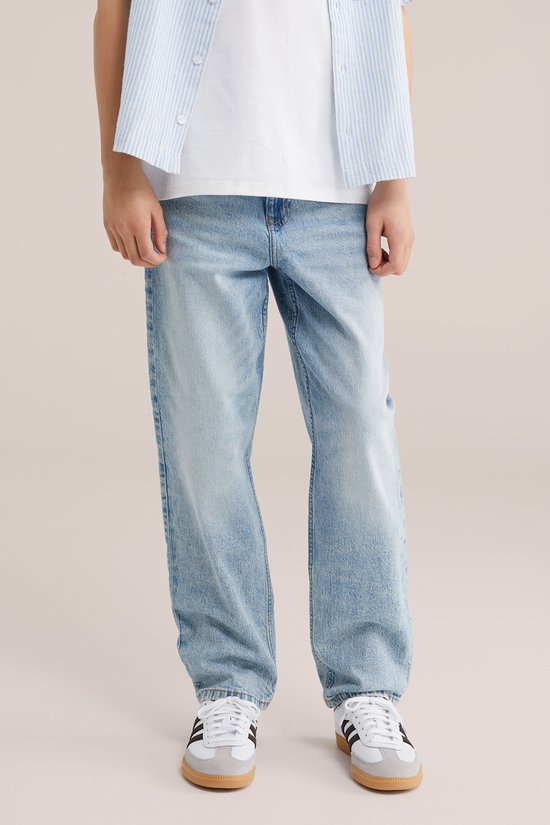 Jongen in een lichtblauwe gestreepte korte mouw overhemd en lichte jeans.