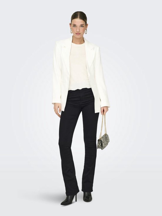 Model in zwarte flared jeans, wit shirt, witte blazer, met zilveren tasje.