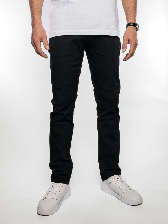Homme portant un jeans Brams Paris noir, modèle Danny, avec stretch, longueur 36, avec des baskets blanches.