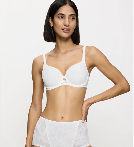 Model met een witte kanten beugel-bh en bijpassende high-waist slip. Zittend op een bankje.
