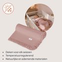 Lichtroze mousseline dekentje met wafelstructuur, franjes. Baby slaapt in ledikant, gedekt met dekentje.