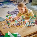 Une fille joue avec un set de centre commercial LEGO Friends. Une construction blanche, rose et verte avec des personnages et des meubles.