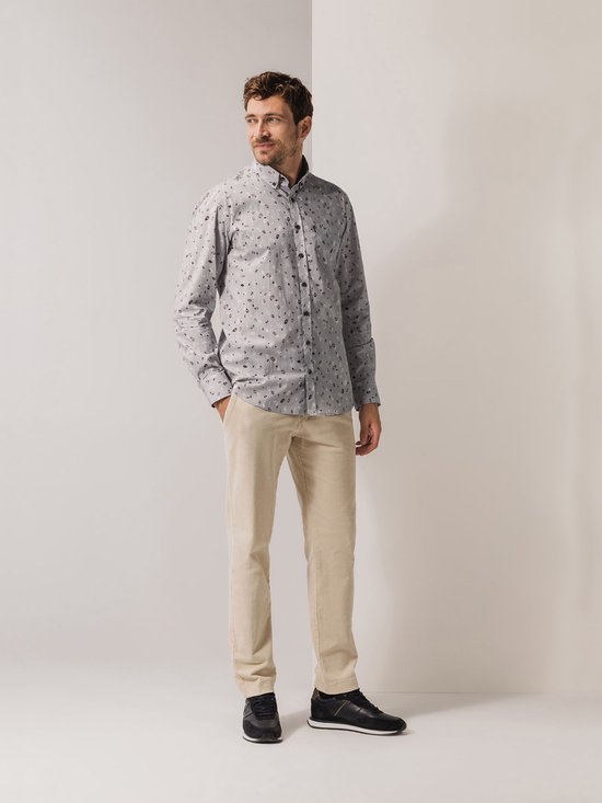 Man met een grijs overhemd met bloemenprint en beige broek.