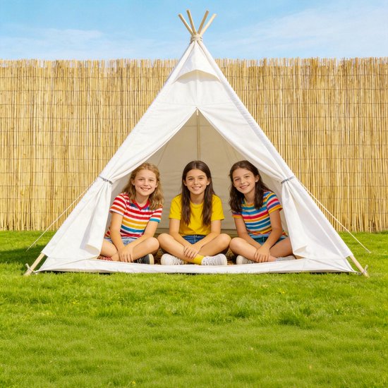 Drie lachende meisjes in kleurrijke T-shirts in een witte tipi, voor een bamboe schutting.