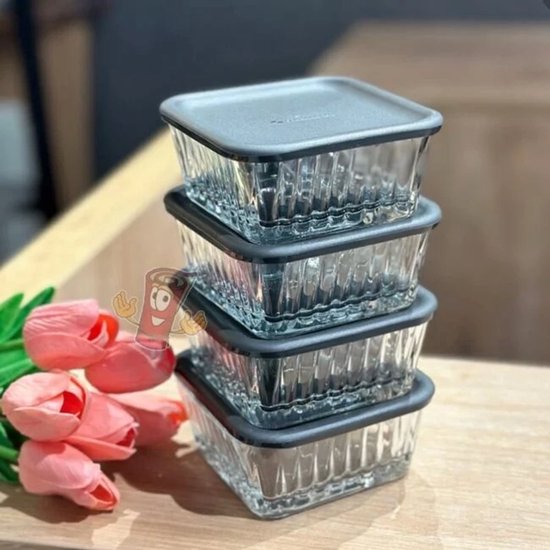 Stapel van vier Pasabahce Frezya voedselcontainers van glas met geribbelde zijkanten en zwarte deksels, naast roze tulpen.