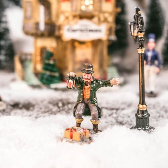 Man met lantaarn bij cadeaus op straat in een besneeuwd dorp.