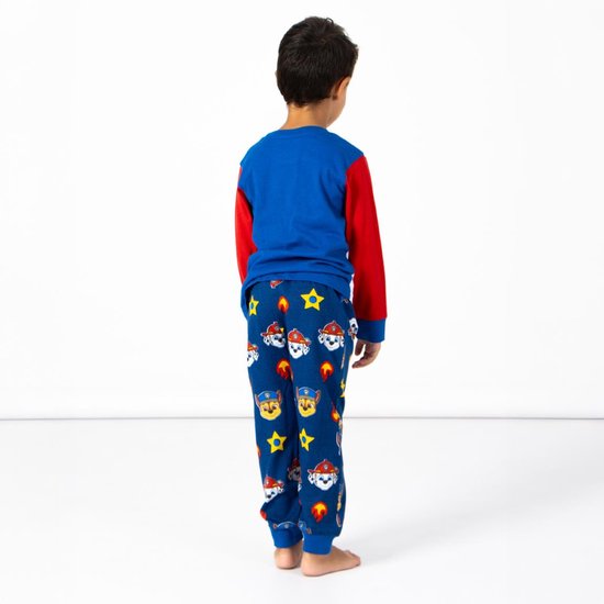 Jongen in blauwe pyjamabroek met Paw Patrol-print van Chase en Marshall, rode mouwen en blauw shirt.