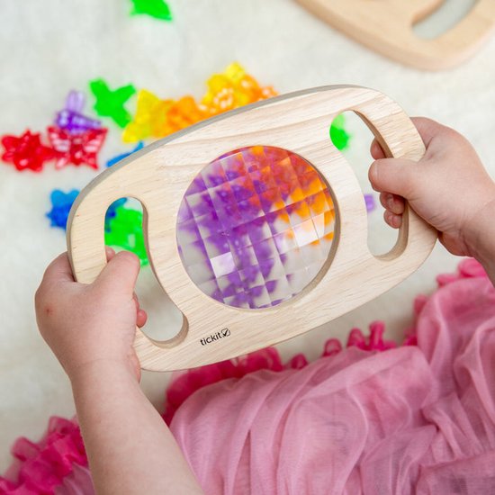Enfant tenant un kaléidoscope en bois avec des motifs violets.