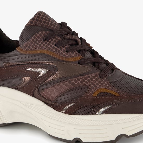 Sluiting van bruine sneaker met slangenprint en zilveren details.