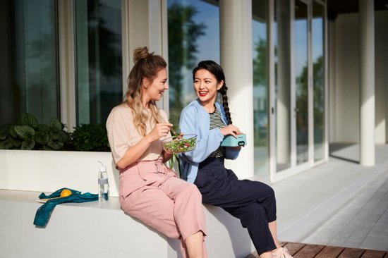 Twee vrouwen met lunch, een Mepal waterfles met groene dop en band staat ernaast.