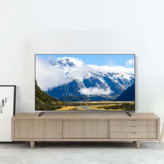 Grote flatscreen tv met een berglandschap op het scherm, geplaatst op een houten dressoir.