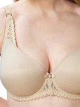 Gros plan d'un soutien-gorge à armatures beige avec un motif en losange sur les bonnets et de la dentelle décorative.