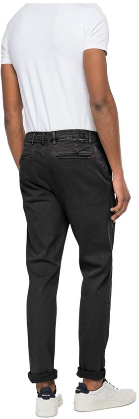 Man van achteren gezien in een witte T-shirt en zwarte jeans met witte sneakers.