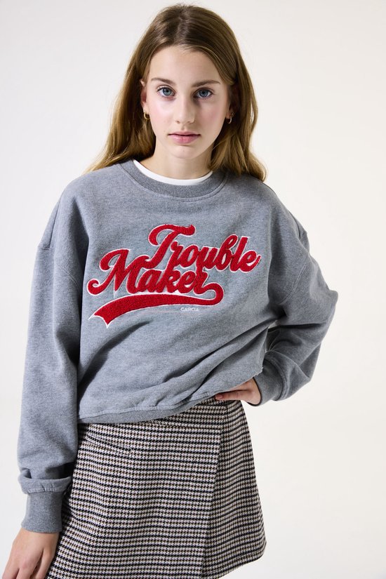 Sweatshirt gris Garcia avec texte rouge 'Trouble Maker' et jupe à carreaux.