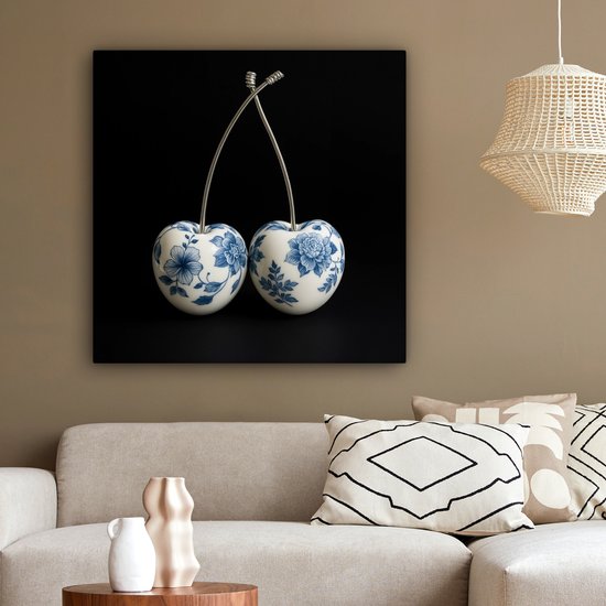 Delfts blauwe kersendecoratie aan de muur boven een bank in een woonkamer.