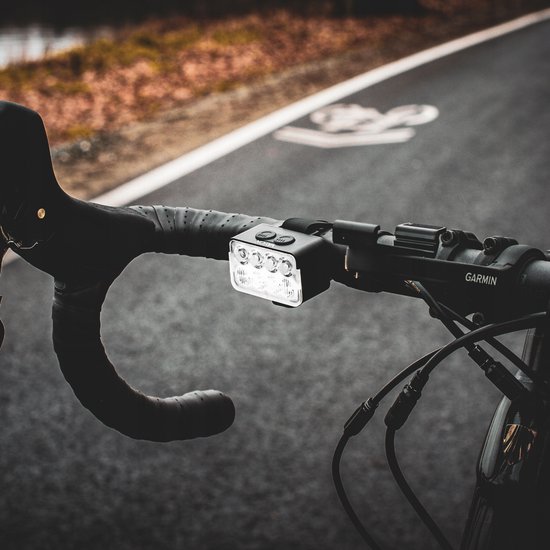 Wit Vayox fiets voorlicht gemonteerd op een fietsstuur met Garmin stuurcomputer.