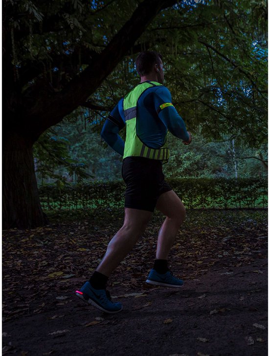 Man joggend in het donker met een fluoriserend geel en blauw sportshirt met reflecterende details.
