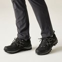 Zwarte wandelschoenen met grijze accenten en veters, gedragen door een persoon in een grijze broek.
