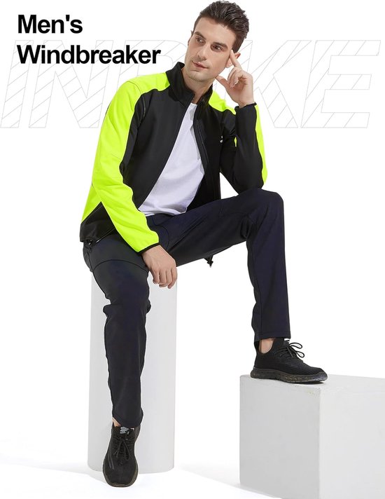 Man zittend op een kruk, draagt een zwarte jas met neongele mouwen, "Men's Windbreaker" in tekst.