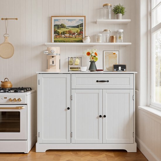 Witte keukenkast met een gesloten deur links en een open gedeelte rechts. Bovenop staat een crèmekleurige koffiemachine en mokken.