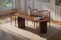 Eettafel van donker hout met een ovaal blad, omringd door houten stoelen met gevlochten zittingen.