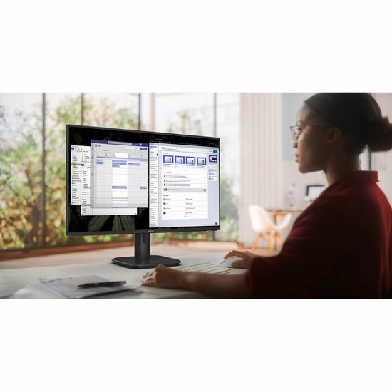 Vrouw met bril gebruikt een zwarte Philips monitor in een lichte kantoorruimte.