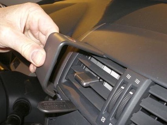 Une main monte un clip de tableau de bord gris à côté d'une grille de ventilation dans une voiture.