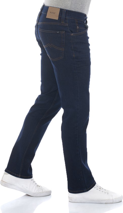 Man in donkerblauwe, rechte jeans met oranje stiksels en witte sneakers, loopbeweging.