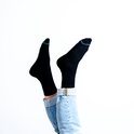 Geknoopte blauwe schoenen en zwarte sokken met blauwe teenranden, gedragen door iemand die op zijn hoofd staat.