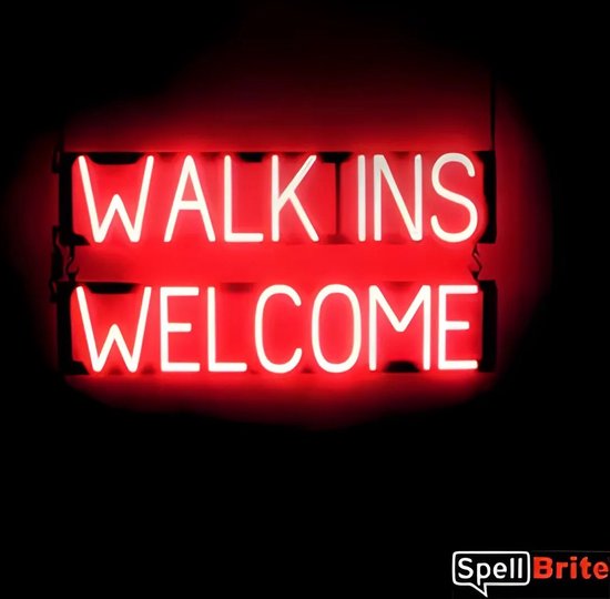 Panneau néon rouge avec le texte "WALK INS WELCOME", éclairé par des lettres LED blanches sur fond noir.