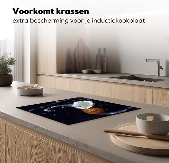 Een keuken met een inductiebeschermer met een kokosnoot en waterplassen op het aanrecht.