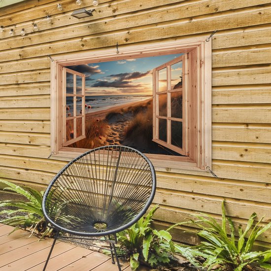 Tuinposter met houten raam, strand met duinen bij zonsondergang, aan een houten schuur met stoel.